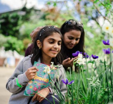Girl with Easter activity booklet and mother looking at spring flowers in Eden's Med Biome